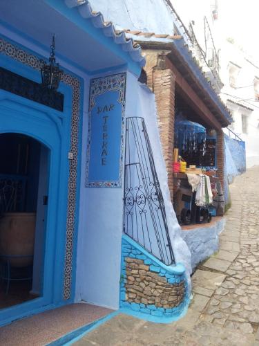 a blue building with a bench on the door at Hôtel Dar Terrae in Chefchaouene
