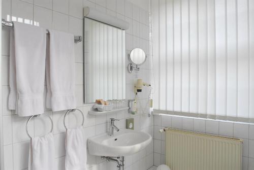 Baño blanco con lavabo y espejo en Kurhotel Fürstenhof by David, en Blankenburg