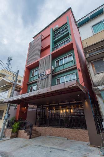 a red building with a balcony on top of it at Let's Zzz Bangkok in Bangkok