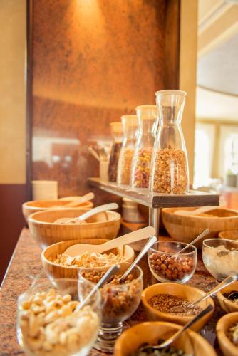 a buffet with bowls of food and jars of nuts at Hotel Wegner - T h e culinary art hotel in Hannover