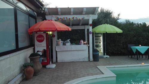 a drink stand with an umbrella next to a pool at L'Isola Felice e Trulli Sotto Le Stelle in Castellana Grotte