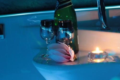 two wine glasses and a bottle and a candle on a counter at Kuredu / Uroa w Krainie Alicji in Ełk