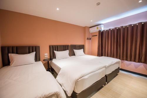 a hotel room with two beds and a window at Let's Zzz Bangkok in Bangkok