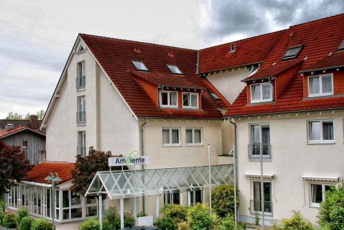 ein großes weißes Gebäude mit rotem Dach in der Unterkunft Hotel Ambiente Walldorf in Walldorf