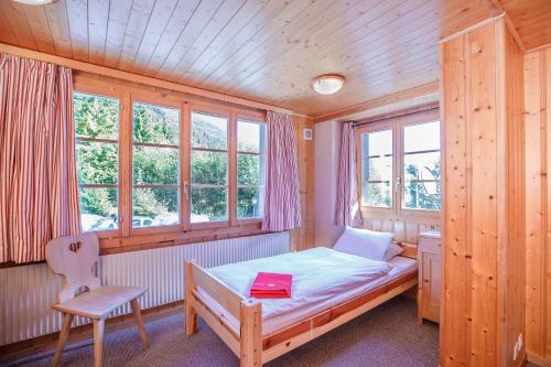 a bedroom with a bed and a chair and windows at Guest House du Grand Paradis - On Piste in Champéry