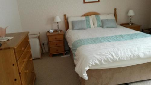 a bedroom with a bed and a dresser with a night stand at 2 The Noust Self Catering in Saint Margarets Hope