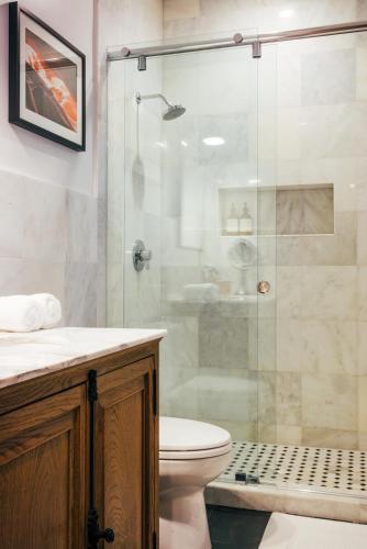 a bathroom with a toilet and a glass shower at Renovated Historic Coconut Grove Cottage Home in Miami