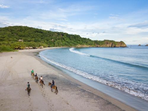 a group of people riding horses on the beach at Morgan's Rock in San Juan del Sur