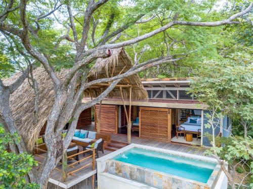 a house with a swimming pool next to a tree at Morgan's Rock in San Juan del Sur