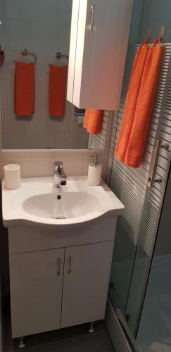 La salle de bains est pourvue d'un lavabo blanc et de serviettes orange. dans l'établissement Orhideja Osijek, à Osijek