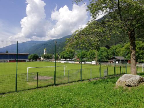 a soccer field with a fence and a tree at Attico Abbraccio di Luce in Spiazzo