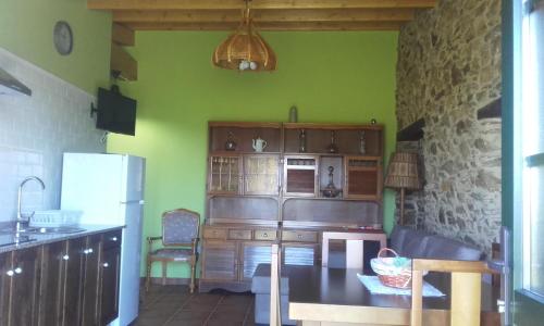 a kitchen with green walls and a table and a refrigerator at A Minguxaina in Ribadeo