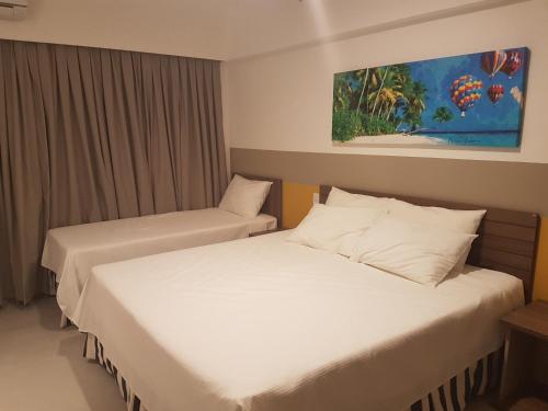 two beds in a hotel room with white sheets at Apartamento em Resort Olímpia FNGN in Olímpia