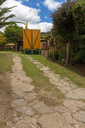 a dirt road with a yellow gate on the side of it at Los Vagones de William in Tibasosa