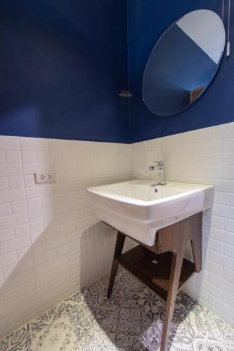 a bathroom with a white sink and a mirror at Let's Zzz Bangkok in Bangkok