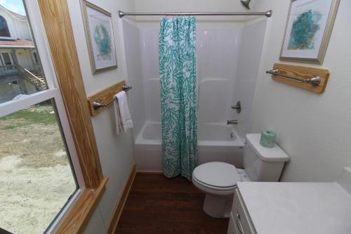 a bathroom with a toilet and a shower curtain at Whalebone Ocean Cottages by KEES Vacations in Nags Head