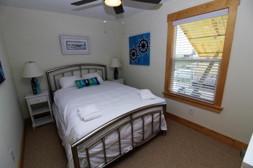 a bedroom with a bed with white sheets and a window at Whalebone Ocean Cottages by KEES Vacations in Nags Head