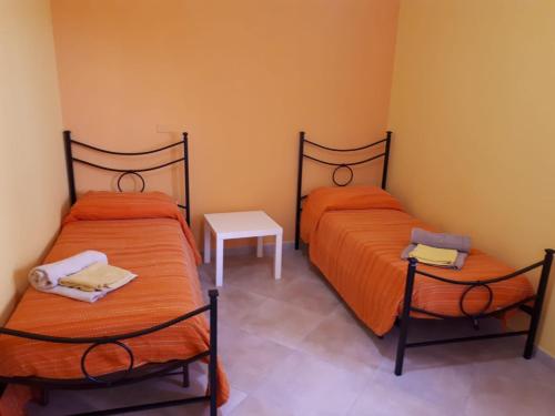 2 bedden met oranje lakens in een kamer bij La Casa Dei Colori in Zafferana Etnea