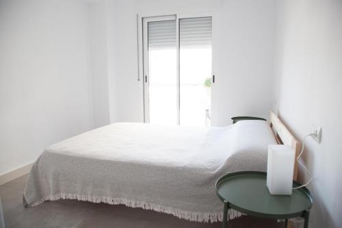 ビリャホヨサにあるBeachfront apartmentの白いベッドルーム(ベッド1台、テーブル付)