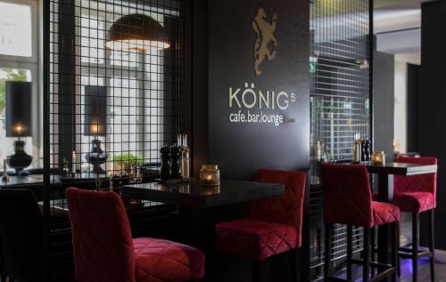 a restaurant with red chairs and a sign on the wall at König`s Hotel am Schlosspark in Rheda-Wiedenbrück