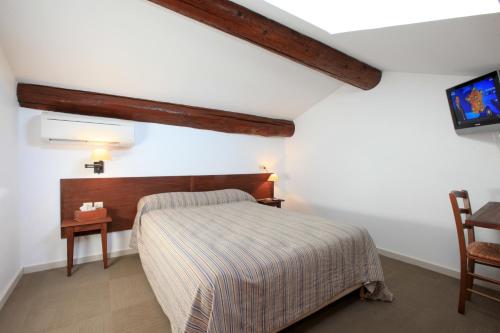 a bedroom with a bed and a table and a tv at Domaine Les Mejeonnes in Valaurie