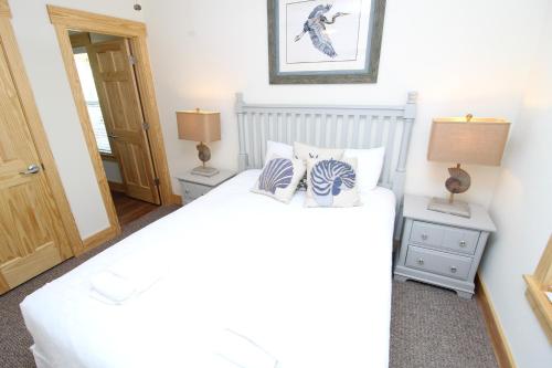 a bedroom with a white bed and two lamps at Whalebone Ocean Cottages by KEES Vacations in Nags Head