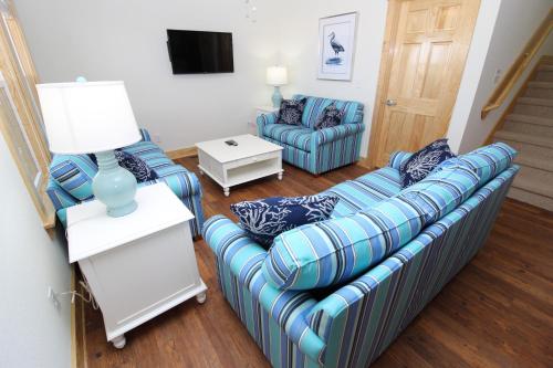 a living room with a blue couch and two chairs at Whalebone Ocean Cottages by KEES Vacations in Nags Head