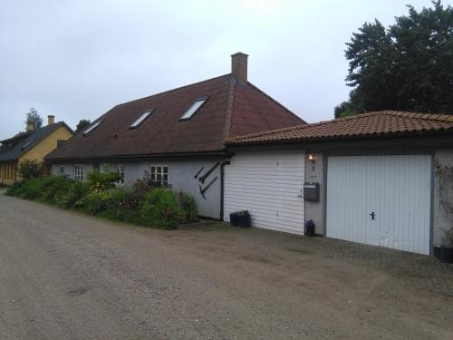 Casa blanca con techo marrón y entrada en Langøhuset, en Langebæk
