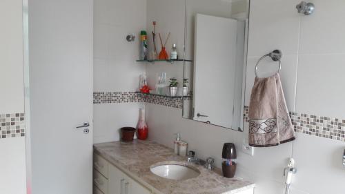 a bathroom with a sink and a mirror at Pitangueiras 3 suítes com vista para o mar in Guarujá