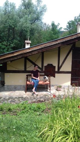 a woman sitting on a bench with a dog at Горска къща в Елена Петроф хоф in Elena