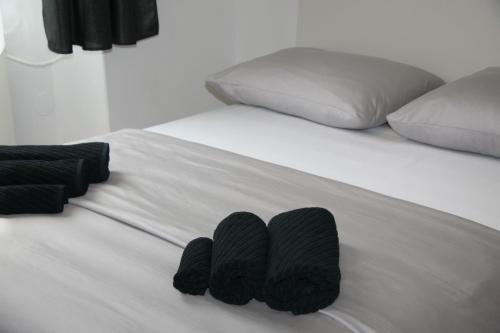 ein weißes Bett mit schwarzer Bettwäsche und Kissen darauf in der Unterkunft Stylish Apartment in City Center in Pula