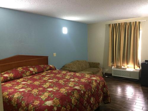ein Schlafzimmer mit einem Bett, einem Sofa und einem Fenster in der Unterkunft Briarwood Inn in Pine Bluff