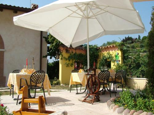 a patio with tables and chairs and an umbrella at El Pendola in Fumane