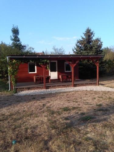 a red cabin with a porch and benches in a field at Ubytování v Anenském údolí in Linhartice