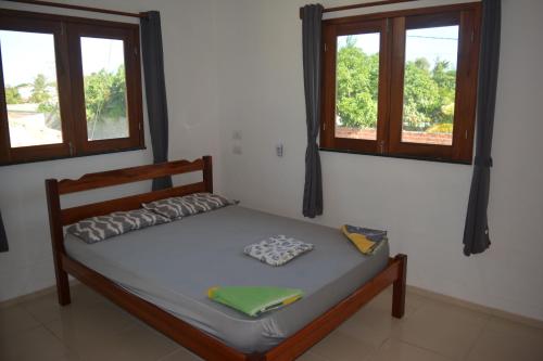 a bed in a room with two windows at Casa do Sol in Paracuru