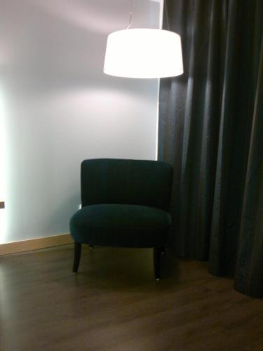 a green chair sitting in a room with a lamp at Hotel Mercure Braga Centro in Braga