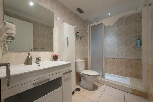 Un baño con inodoro, lavabo y ducha. en Mogan Beach | CarmitAtHome, en Puerto de Mogán