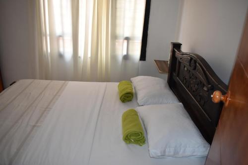 a bedroom with a bed with white sheets and green pillows at Hostal Palohe Taganga in Taganga