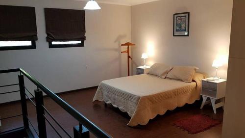 1 dormitorio con 1 cama, 2 mesas y 2 ventanas en Duplex temporario Santa Fe en Santa Fe