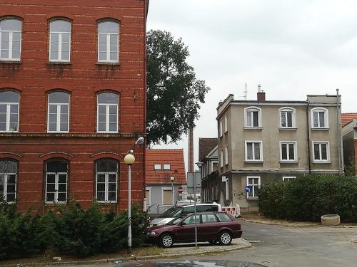 een auto geparkeerd op een parkeerplaats naast een bakstenen gebouw bij My Secret Place. in Zielona Góra