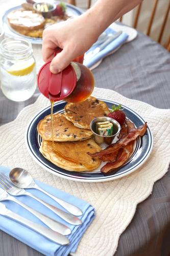a person is pouring syrup on a plate of pancakes at Camden Windward House in Camden