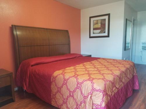 a bedroom with a large bed with a red bedspread at Monte Carlo Motel in New Orleans