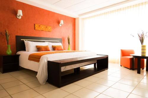1 dormitorio con 1 cama con pared de color naranja en Inn Express Hotel Tula, en Tula de Allende