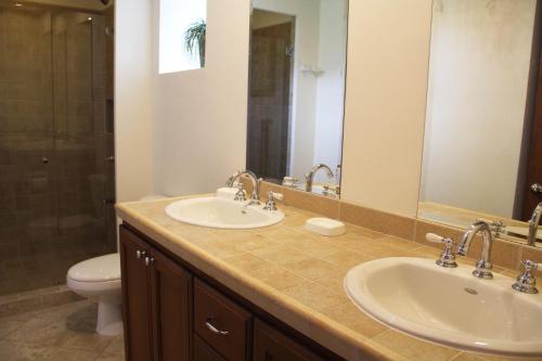 y baño con 2 lavabos, aseo y espejo. en Los Suenos Resort Veranda 2B by Stay in CR, en Herradura