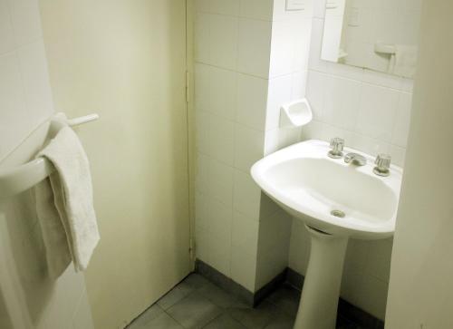 a white bathroom with a sink and a mirror at Avenida Hotel in Junín