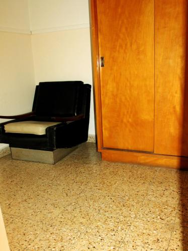 a black chair sitting in a room next to a door at Avenida Hotel in Junín
