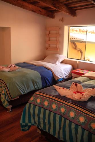 a bedroom with two beds and a window at Eureka Lodge in Ollantaytambo