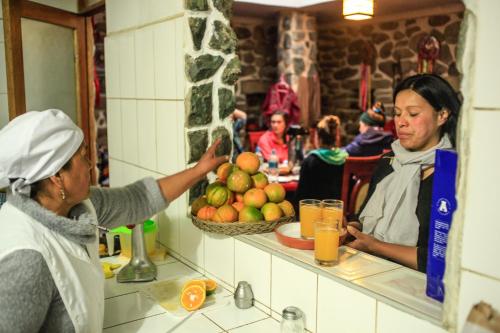 a woman standing in a kitchen preparing food at Eureka Lodge in Ollantaytambo