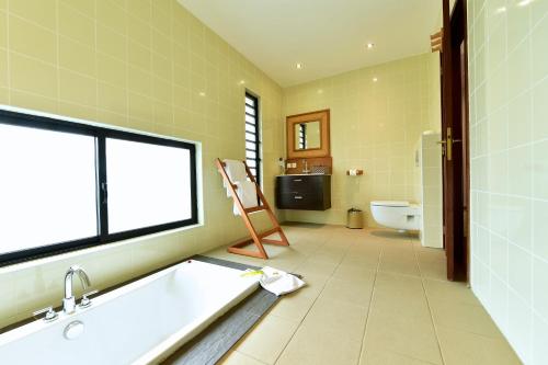 a bathroom with a tub and a sink and a toilet at Hotel Paradis d'Ouvéa in Fayaoué