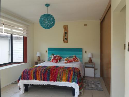 um quarto com uma cama com um cobertor colorido em Casa en Pingueral em Dichato